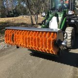 Sopvals med orange borste monterad på hjullastare på grusväg